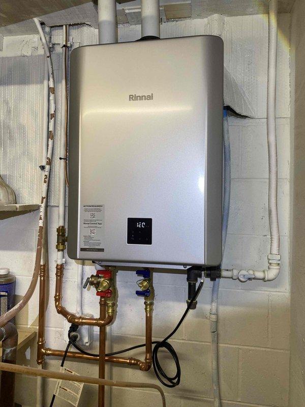 Successfully removed existing tankless water heater and metal venting, then installed new Rinnai RX199iN unit (field converted to LP) with 199,000 BTU capacity as recommended by manufacturer. Modified existing water lines to accommodate new unit, installed tankless flush valve kit for isolation and future service, altered 3/4" gas piping, and installed 2" PVC fresh air intake and exhaust venting through sill plate with partial ceiling removal in mechanical room. Connected 3/4" PVC condensate line to floor drain and temporarily relocated water conditioner during installation before returning it to original position upon completion.