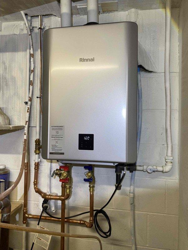 Successfully removed existing tankless water heater and metal venting, then installed new Rinnai RX199iN unit (field converted to LP) with 199,000 BTU capacity as recommended by manufacturer. Modified existing water lines to accommodate new unit, installed tankless flush valve kit for isolation and future service, altered 3/4" gas piping, and installed 2" PVC fresh air intake and exhaust venting through sill plate with partial ceiling removal in mechanical room. Connected 3/4" PVC condensate line to floor drain and temporarily relocated water conditioner during installation before returning it to original position upon completion.