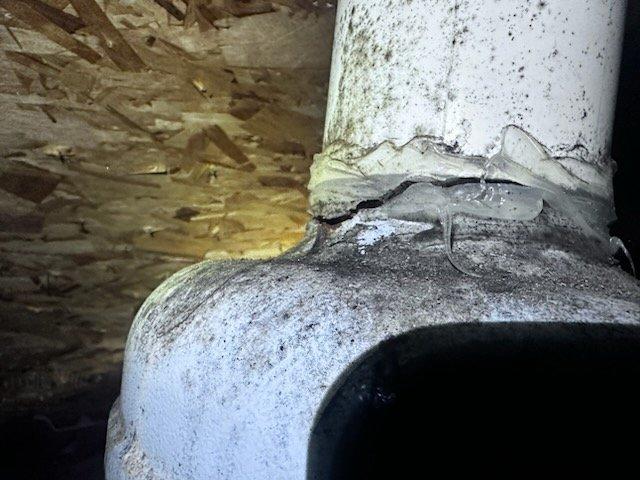 Inspected attic ventilation system and identified significant damage to PVC vent pipe joint with visible cracking, separation, and failed sealant. Documented moisture intrusion and potential mold accumulation at connection point where vent fan is leaking. Unable to complete repair during initial visit due to insufficient ladder height; scheduled return visit with appropriate extension ladder to access roof and complete necessary repairs.