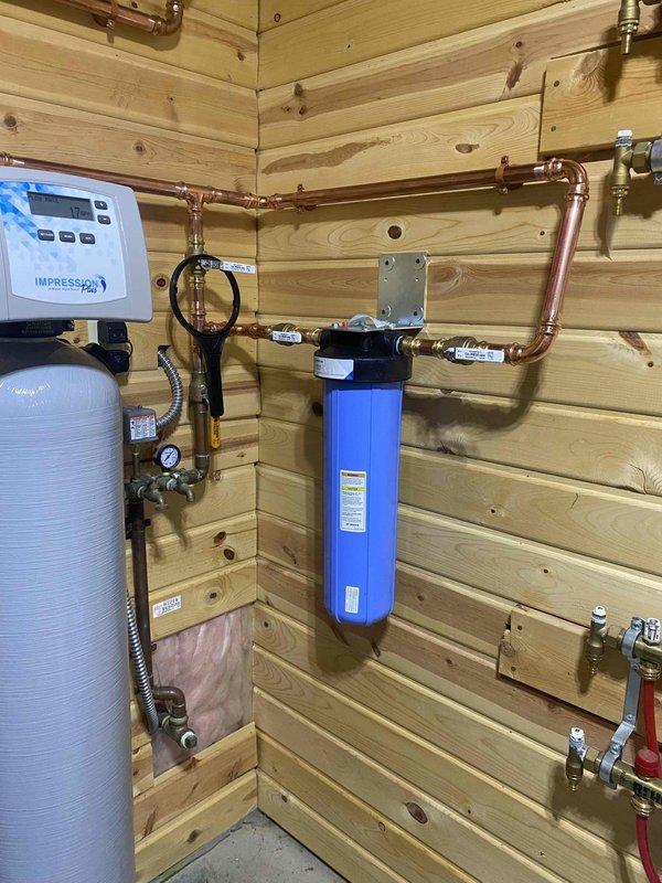 Removed existing water conditioning units and installed a complete water treatment system including a Pentek Big Blue 20" x 4.5" wall mounted filter with Hydronix 1 micron polyspun sediment filter cartridge, Water Right IMPBF-1054AN acid neutralizer with calcite, and Water Right IMP-1044 water softener with new brine tank. System was installed with 1" copper piping, complete with 3 valve bypass assembly and discharge routed to floor drain.