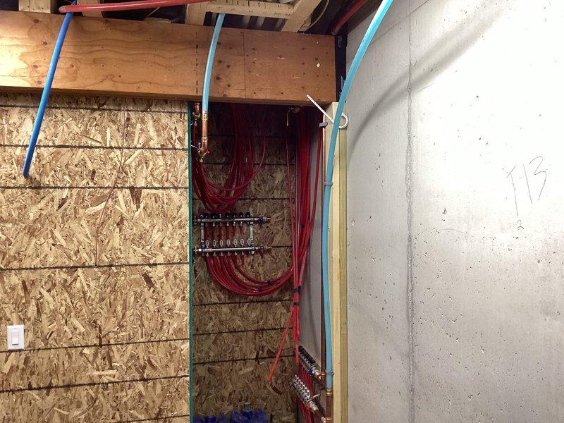 Inspected hydronic infloor heating system on main floor and identified damaged tubing caused by nail penetration requiring replacement. Documented unconnected manifold and absence of glycol in the system. Met with insurance adjuster on-site to evaluate repair scope, which will involve opening drywall and repiping the infloor heat system in this new construction.