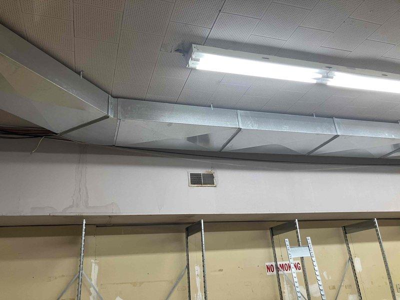 Performed system balance test and airflow evaluation following office wall removal in commercial space. Inspected HVAC ductwork and identified missing return air grill where wall was previously located. Documented ceiling-mounted ductwork configuration and system layout with photos. Provided estimate for airflow testing and return grill installation to ensure proper system operation and balance as required by inspector.