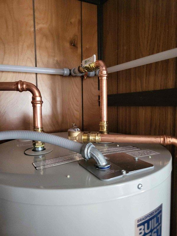 Installed a 40-gallon Bradford White electric water heater in utility closet as return work. Configured new copper supply lines with brass fittings and pressure relief valve, connected white flexible PEX tubing to existing plumbing system, and completed all necessary connections to bring unit into full operation.