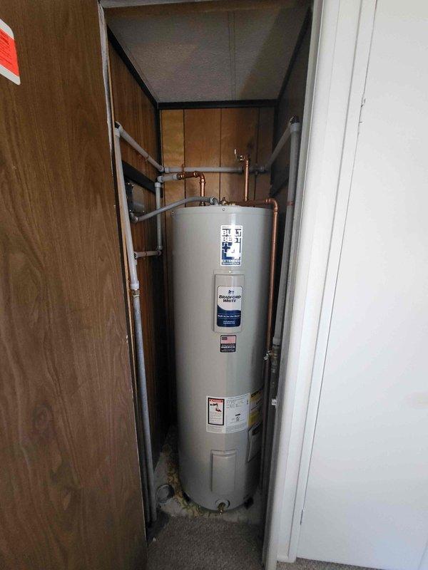 Installed a 40-gallon Bradford White electric water heater in utility closet as return work. Configured new copper supply lines with brass fittings and pressure relief valve, connected white flexible PEX tubing to existing plumbing system, and completed all necessary connections to bring unit into full operation.