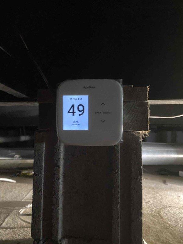 Installed dehumidifier system in crawl space with Aprilaire digital monitoring control displaying humidity levels and operational status. Completed installation of condensate drain line and pump for humidifier system, routing white PVC drainage piping through crawl space structure with proper support and connections to existing HVAC infrastructure.
