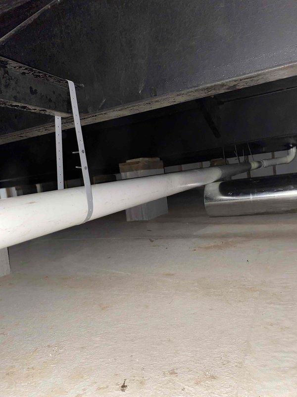 Installed dehumidifier system in crawl space with Aprilaire digital monitoring control displaying humidity levels and operational status. Completed installation of condensate drain line and pump for humidifier system, routing white PVC drainage piping through crawl space structure with proper support and connections to existing HVAC infrastructure.