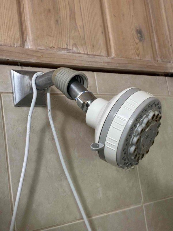 Completed de-winterization service for three-bathroom cottage. Addressed dripping shower head by installing new wall-mounted fixture with flexible hose connection to tiled bathroom wall. Replaced outdoor spigot to resolve exterior leak, with copper supply line work performed in exposed ceiling/utility area. All fixtures tested and confirmed operational for seasonal opening.