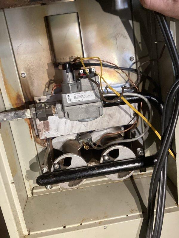 Responded to no heat call on 25-year-old gas furnace. Upon inspection, found severe flame rollout condition with extensive rust and corrosion throughout heat exchanger and combustion chamber. Unit exhibited failed thermocouple that would not maintain pilot flame, along with visible deterioration of burner assembly and cabinet housing showing significant oxidation and moisture damage. Due to age of equipment, compromised heat exchanger integrity, and unsafe operating conditions presenting carbon monoxide risk, recommended and customer approved complete furnace replacement. Documented existing conditions with photos showing rusted combustion components, corroded gas valve assembly, and deteriorated cabinet interior before system disconnect.