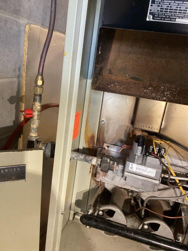 Responded to no heat call on 25-year-old gas furnace. Upon inspection, found severe flame rollout condition with extensive rust and corrosion throughout heat exchanger and combustion chamber. Unit exhibited failed thermocouple that would not maintain pilot flame, along with visible deterioration of burner assembly and cabinet housing showing significant oxidation and moisture damage. Due to age of equipment, compromised heat exchanger integrity, and unsafe operating conditions presenting carbon monoxide risk, recommended and customer approved complete furnace replacement. Documented existing conditions with photos showing rusted combustion components, corroded gas valve assembly, and deteriorated cabinet interior before system disconnect.
