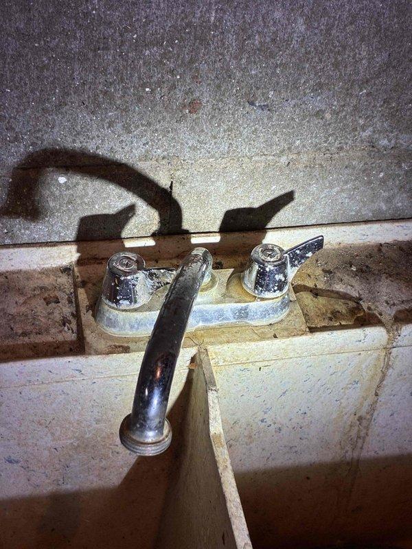 Completed cottage de-winterization service addressing multiple plumbing leaks. Replaced deteriorated utility sink faucet showing extensive corrosion and mineral buildup, installed new outdoor hose bib on exterior wall to eliminate leak at spigot, and replaced faulty water heater valve. All fixtures tested and verified operational with no leaks detected upon completion.