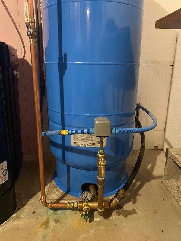 Removed existing pressure tank system from basement utility area. Installed new 80-gallon Well-X-Trol pressure tank with complete tank tee assembly, pressure switch, and gauge. Connected all copper piping and brass fittings to integrate system with existing water softener unit, ensuring proper operation of well water storage and distribution system.