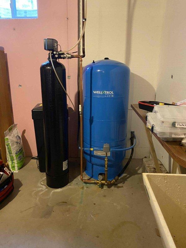 Removed existing pressure tank system from basement utility area. Installed new 80-gallon Well-X-Trol pressure tank with complete tank tee assembly, pressure switch, and gauge. Connected all copper piping and brass fittings to integrate system with existing water softener unit, ensuring proper operation of well water storage and distribution system.