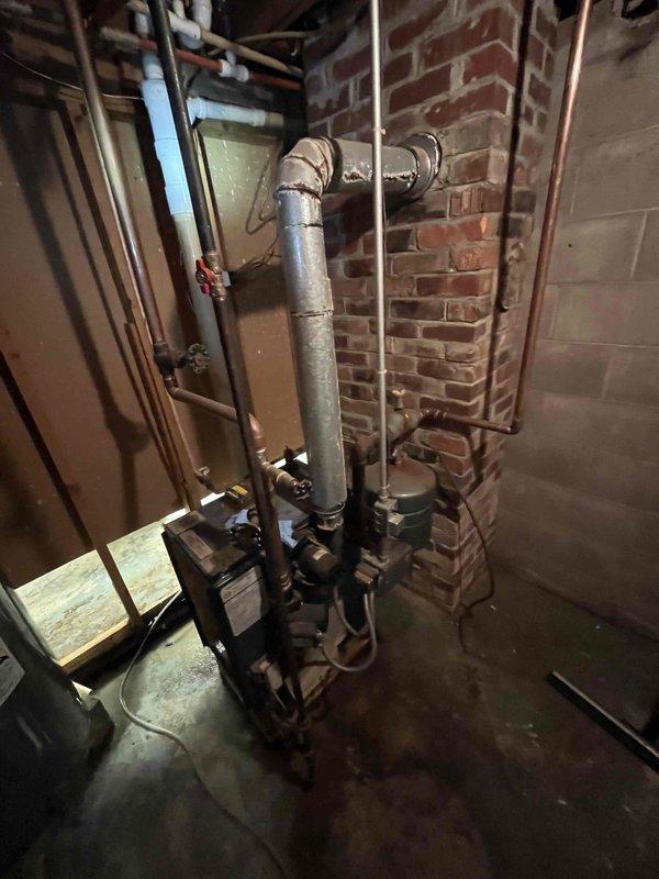 Responded to reported water leak in basement area. Conducted thorough investigation of boiler system, water heater, and visible plumbing connections but found no evidence these were the source of the water accumulation on floor. Leak may be related to foundation issue requiring further specialist evaluation. During inspection, identified critical safety hazard with boiler exhaust piping showing torn seams along multiple sections, creating potential for carbon monoxide and combustion gases to vent into living space. Documented severely corroded boiler system showing extensive rust, deterioration, and age-related wear throughout components and piping. Given equipment is over 30 years old with significant deterioration, recommended system replacement rather than repair. Provided comfort advisor consultation for replacement options due to equipment condition and safety concerns.