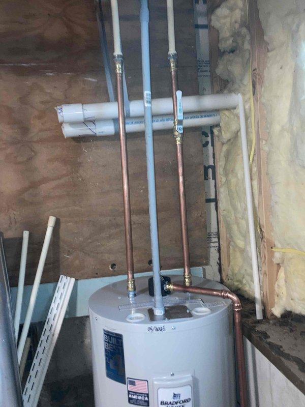 Completed installation of a 30-gallon electric Bradford White water heater in basement utility area. Connected all necessary copper supply lines and PVC drainage pipes to the unit, ensuring proper fittings and secure connections at the top of the heater. Installation performed in accordance with manufacturer specifications and local plumbing codes.