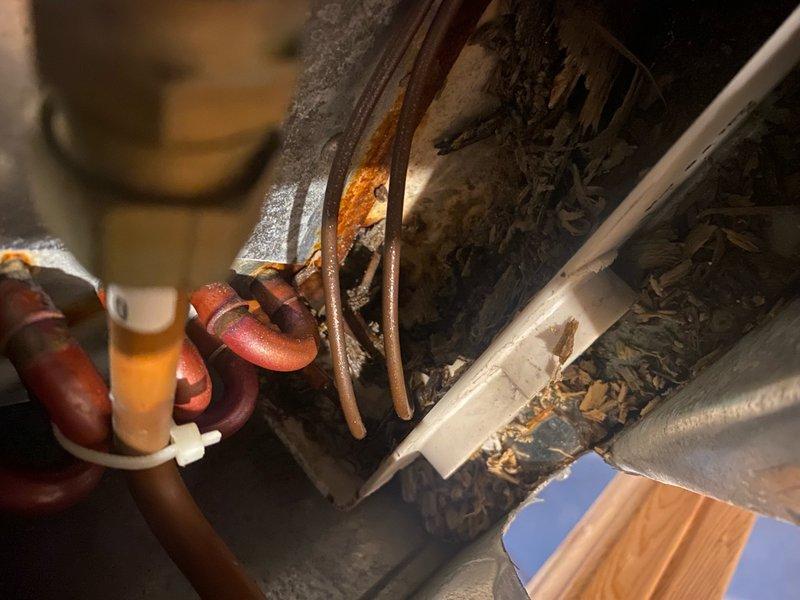 Responded to emergency service call for AC unit leaking water across floor. Upon inspection, found condensate drain line completely plugged, causing water overflow from drain pan. Cleared blockage from drain line, tested drainage flow, and verified proper operation. Unit showed signs of age with deteriorated insulation on refrigerant lines and accumulated debris around evaporator coil area, but system resumed normal function after drain clearing.