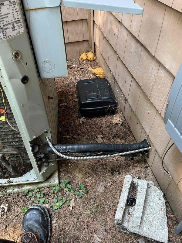 Responded to no cooling call on 10-year-old air conditioning system. Upon arrival, found outdoor condensing unit completely inoperative with no power. Investigated electrical supply and discovered rodent damage to incoming line power cable, which had caused a short circuit. Removed damaged wiring and ran new power cable from crawlspace to condenser disconnect. Restored power to unit, verified proper operation, and confirmed system cooling normally. Photographed damaged wiring and completed repairs.