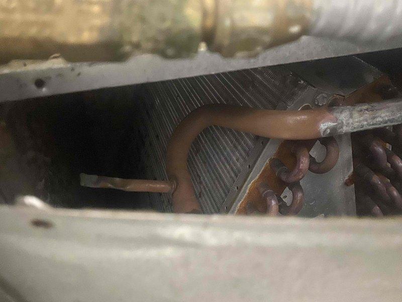 Responded to no cool call on 30-year-old air conditioning system. Upon inspection, found unit operating with low refrigerant charge and heavily soiled evaporator coil with significant corrosion on copper tubing. Documented system condition with photos showing deteriorated coil assembly, corroded refrigerant lines, and extremely dirty air filter restricting airflow. Provided estimate for necessary repairs given age and condition of equipment.