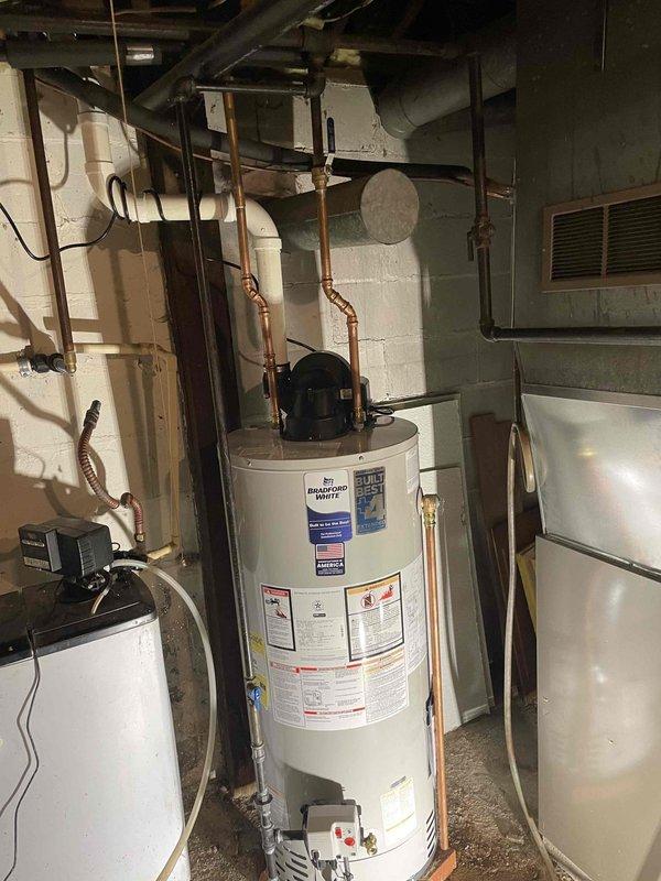 Responded to no hot water complaint on 16-year-old residential water heater displaying ignition failure code. Upon inspection, unit was found in vacation mode and exhibited signs of age-related failure beyond economical repair. Removed and properly disposed of existing tanked water heater. Installed new Bradford White tanked water heater in basement utility area, connecting to existing copper supply and discharge lines. Verified all plumbing connections for proper seal, tested temperature and pressure relief valve operation, and programmed control settings. Unit tested and confirmed operational with proper hot water delivery throughout residence.