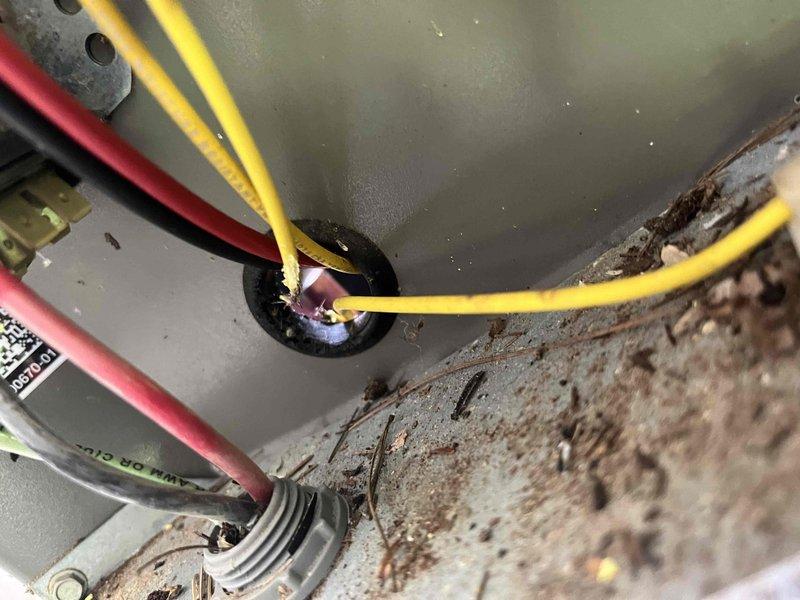Responded to no cooling call on residential HVAC system. Upon inspection, discovered rodent damage to control voltage wiring at the outdoor condenser unit. Multiple wires had been chewed through, interrupting the low-voltage circuit and preventing system operation. Removed damaged wiring sections and installed new control voltage wiring through the condenser cabinet entry point. Secured wiring properly through grommet to prevent future exposure. Noted significant rust and corrosion on condenser cabinet panels and base platform, indicating prolonged moisture exposure. Observed accumulated debris and organic material throughout the unit base requiring attention. After completing wiring repairs, energized system and verified proper operation of all components. Tested cooling cycle through complete run sequence. System restored to normal operation with adequate cooling performance confirmed.
