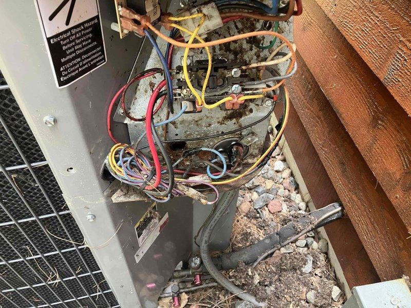 Responded to no cooling call on 20-year-old air conditioning system. Upon inspection, found unit attempting to run but failing to start due to failed capacitor exhibiting severe corrosion and deterioration on terminals and connections. Interior compartment showed extensive debris accumulation and environmental damage from long-term exposure. Replaced defective capacitor with new unit, restored proper electrical connections, and verified system operation. Unit now cooling properly.