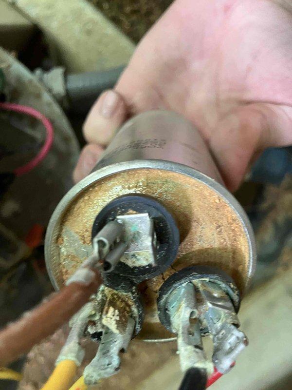 Responded to no cool call on 22+ year old Amana air conditioning system with non-operational outdoor fan. Upon inspection, found failed capacitor with severe corrosion, oxidation, and heat damage at terminals. Replaced defective capacitor and restored system to normal operation.