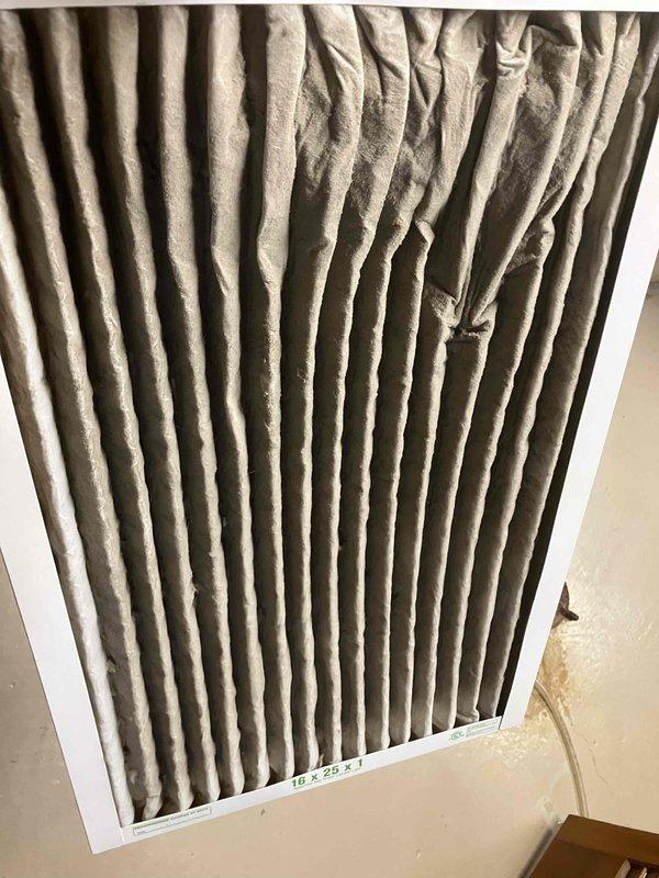 Responded to emergency no-cool call on 25-year-old air conditioning system with frozen evaporator coil. Upon inspection, found severely restricted airflow caused by heavily soiled air filter. Replaced dirty filter with new 16x20x1 pleated filter to restore proper system airflow. Observed blower motor assembly with significant debris accumulation and deterioration, indicating extended maintenance neglect. System operational after filter replacement, restoring cooling capacity to residence.