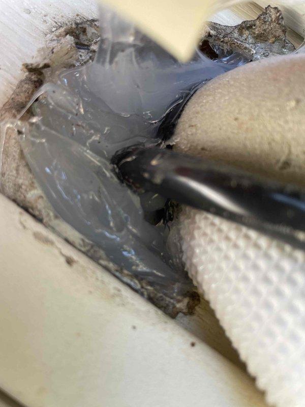 Responded to urgent callback regarding wildlife intrusion through recently installed mini split system penetration. Upon arrival, confirmed bats were entering residence through inadequate sealing around refrigerant line set and condensate drain penetration at rear exterior wall. Pest control had previously identified the mini split piping entry point as the access location. Inspected penetration and found existing sealant had failed, leaving gaps sufficient for wildlife entry. Applied additional clear silicone sealant over existing material to fully seal all openings around copper line set and drain piping where they enter the structure. Verified complete coverage of all gaps and voids at wall penetration point. Documented conditions with photographs showing before and after sealing work. System remains operational with no impact to refrigerant lines or drainage function.