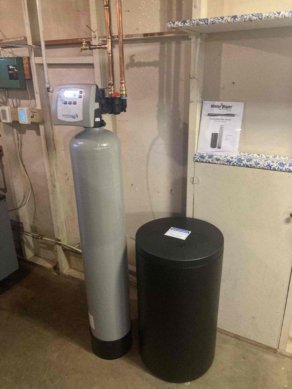 Successfully installed a Water Right IMP1054 water softener system in the basement utility area. Ran new piping from the well connection point to the unit, including 20 feet of 1/2" PEX drain line with proper routing and support. Mounted the digital control head and valve assembly on the tall cylindrical tank, connecting all copper supply lines with brass fittings along the wall. Completed electrical connections to the control box and verified proper operation of the digital display. All plumbing connections were secured with appropriate hangers and clips to ceiling joists. System was tested and confirmed operational, with water test results showing 6 GPG hardness, 0 ppm iron, 7.4 pH, and 90 TDS. Unit includes 10-year warranty on tanks, 5-year warranty on head and valve, and 1-year labor warranty.