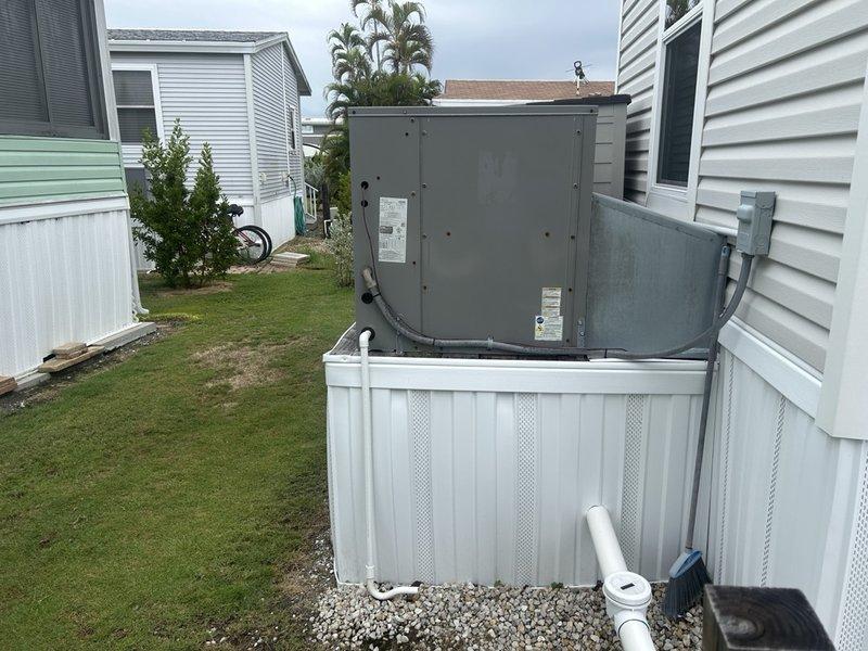 Sanibel, FL - Responded to a no cool complaint on a residential HVAC system located at a mobile home installation. Upon arrival, inspected the outdoor condensing unit and verified the electrical supply at the breaker panel. Documented the system configuration including the unit's position between structures, electrical connections, and surrounding installation conditions. The circuit breakers showed proper amperage ratings with no visible tripping or damage to the electrical panel components. Photographed the outdoor unit and electrical panel for service records to support diagnostic findings and future reference.