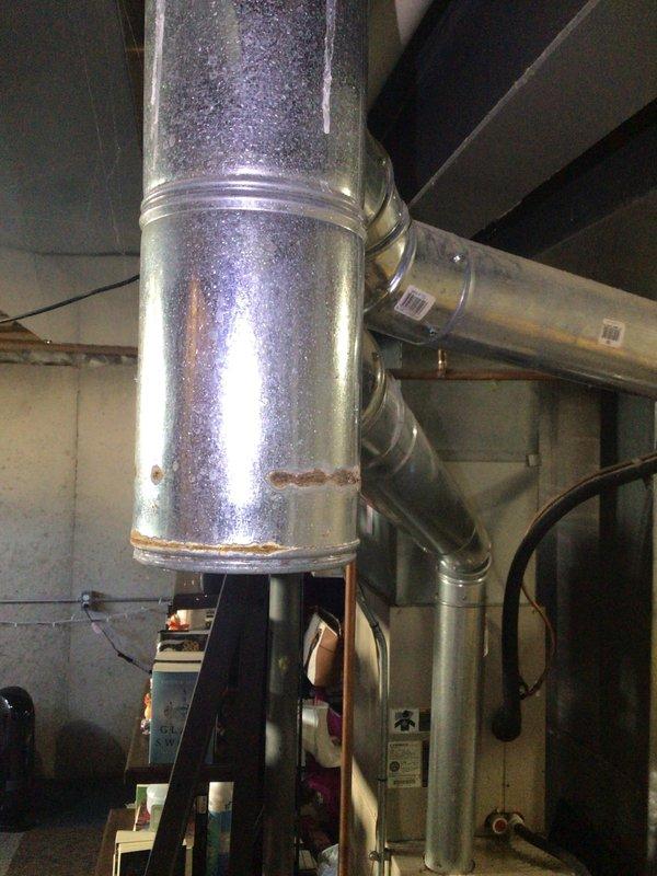 Responded to no heat call for 20-year-old system blowing cold air with unknown error code. Inspection revealed significant corrosion on main vertical duct with compromised connection points at T-junction. Cleaned corroded areas, secured loose connections with appropriate metal bands, and reset system, resolving the error code and restoring proper heat function.
