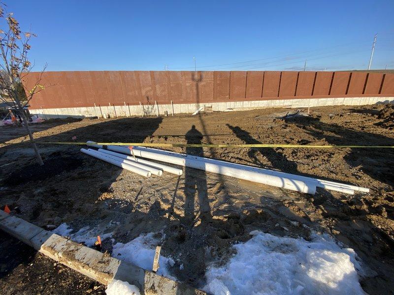 Completed installation of a new 4" discharge line into manhole with water stop per estimate. Work included excavating trench adjacent to foundation, laying and securing PVC piping according to permit specifications (24DRN-00132), and ensuring proper connection to existing drainage system. Photos documented the completed installation showing horizontal and vertical pipe placement with appropriate markers for elevation levels.