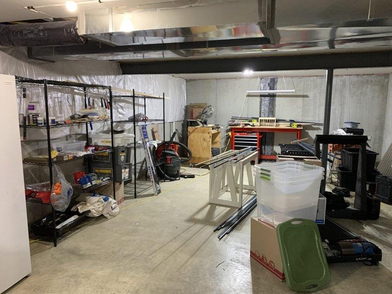 Performed electrical assessment for installation of hallway lighting on main floor and 4-5 receptacles in basement. Evaluated existing console table area with nearby electrical outlet on main floor and surveyed unfinished basement space with concrete flooring, exposed ductwork, and existing storage shelving to determine optimal receptacle placement for improved functionality.