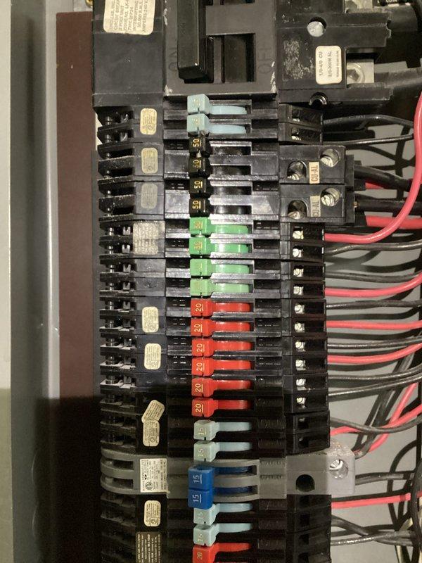 Conducted comprehensive inspection of residential electrical panel featuring multiple circuit breakers with standard color-coding (red, green, blue, gray). Examined wiring connections, verifying proper installation of hot (red/black) and neutral (white) conductors. Panel appears to be in functional condition with appropriate labeling on breakers, though some wire management improvements were recommended at the top section where bundling is dense.