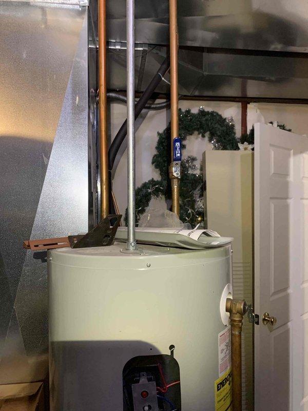 Conducted electrical inspection of residential water heater system, identifying corrosion at the control panel area and examining wiring connections to the thermostat module. Visual assessment revealed properly installed copper and metal piping but noted rust damage requiring attention at the lower section of the tank.