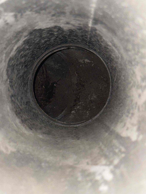 Performed inspection of furnace exhaust flue system. Identified significant soot and debris buildup in the vertical stack requiring cleaning. Examined connecting ductwork and verified proper configuration of PVC venting with P-trap assembly.