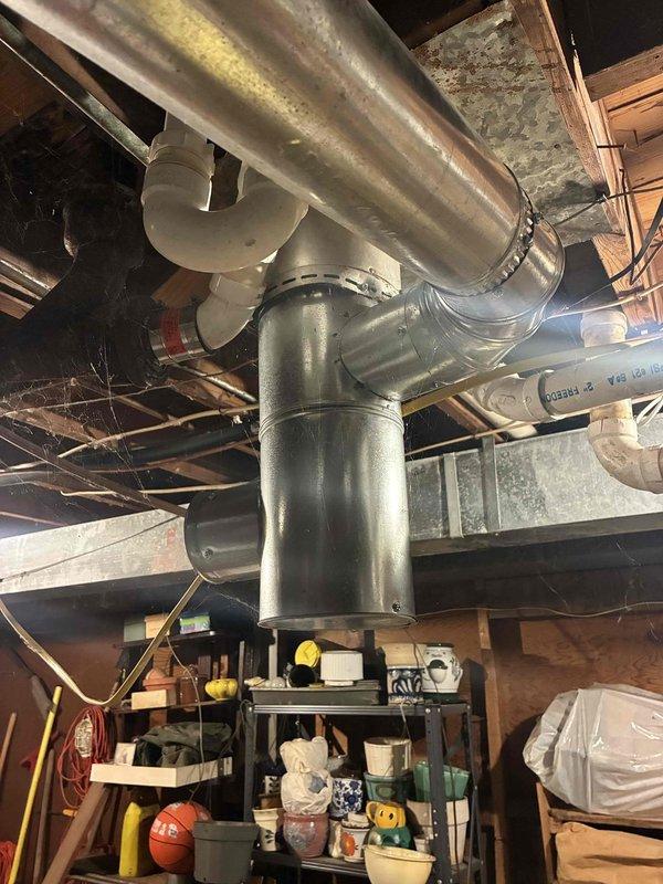 Performed inspection of furnace exhaust flue system. Identified significant soot and debris buildup in the vertical stack requiring cleaning. Examined connecting ductwork and verified proper configuration of PVC venting with P-trap assembly.