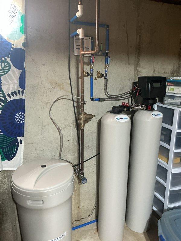 Successfully installed a 50-gallon tall gas water heater with proper permit (#26PLU-04316) and applied required plumbing ID sticker. System was properly connected to existing copper piping in the basement utility area, with all warning labels and specifications visible. Water treatment system was also installed, including two cylindrical filtration tanks and a brine tank with associated PVC piping and digital control unit.