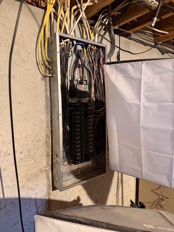 Conducted a free electrical inspection of the main service panel, examining the breaker arrangement, wiring connections, and overall installation integrity. Panel inspection revealed multiple circuits with appropriate wire routing through the upper joists, though noted dense wire bundling that may benefit from improved organization. All breakers appeared properly sized and installed with no signs of overheating or damage observed during the comprehensive safety evaluation.