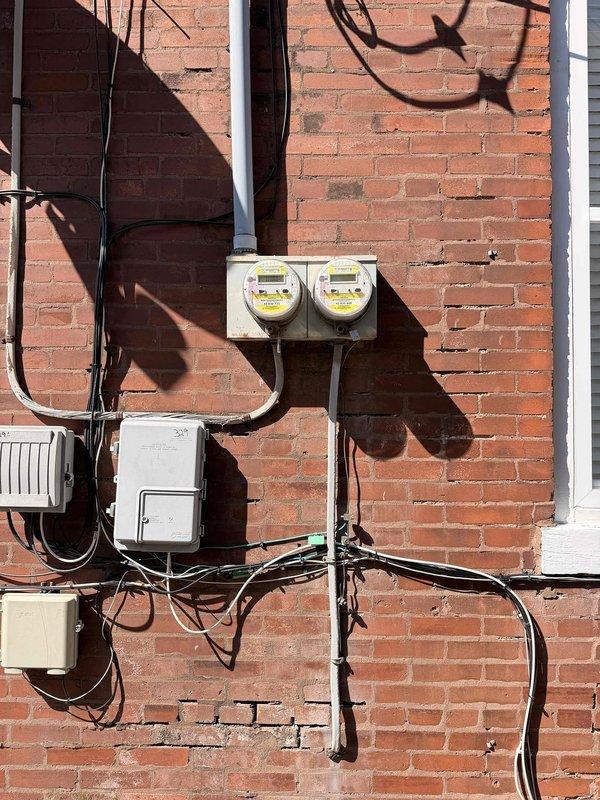 Performed complimentary inspection of residential electrical service entrance as part of membership promotion. Examined utility meter installation (Gridstream RF, Focus AXRe-SD) and surrounding electrical infrastructure. Visual inspection revealed standard Ameren meter setup with proper mounting on brick exterior wall, with associated service panel and conduits in serviceable condition.