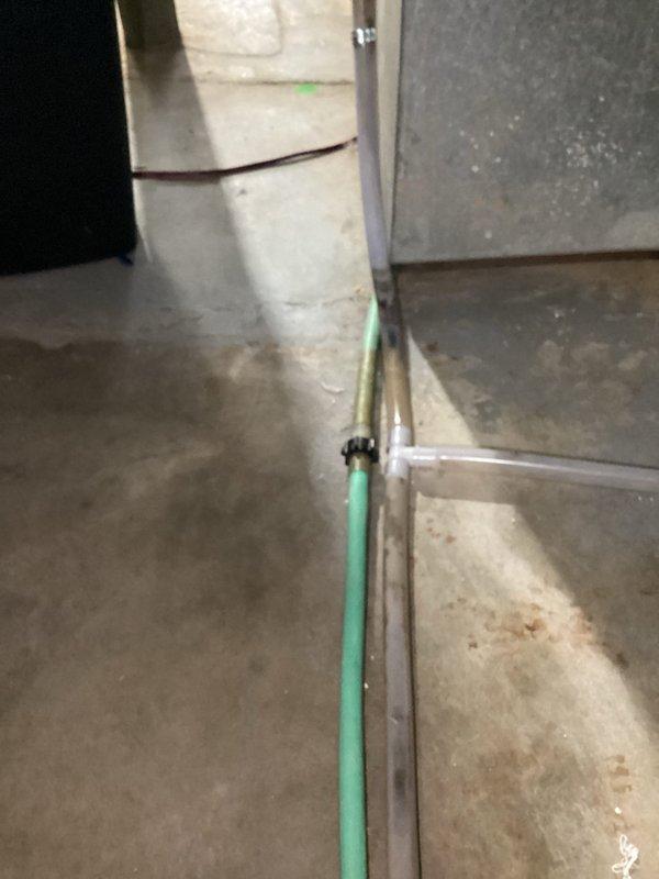 Inspected 7-month-old humidifier system in basement after customer reported mold in humidifier tube and possible standing water at duct connection. Identified water leakage around drain connection and documented moisture patterns on concrete floor. Verified mint-green condensate line routing and connection to drain system.