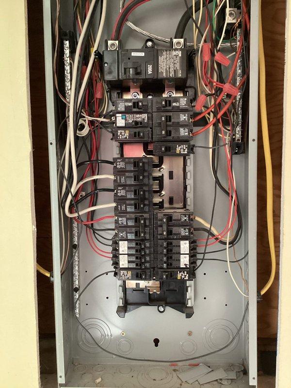 Conducted a comprehensive electrical panel inspection, examining circuit breakers, wiring connections, and load distribution. Documented the panel's internal components including multiple circuit breakers arranged in vertical columns with associated red, white, black, green, and yellow wiring. Verified proper organization of electrical conductors through metal conduits while noting the overall condition of the residential distribution system.