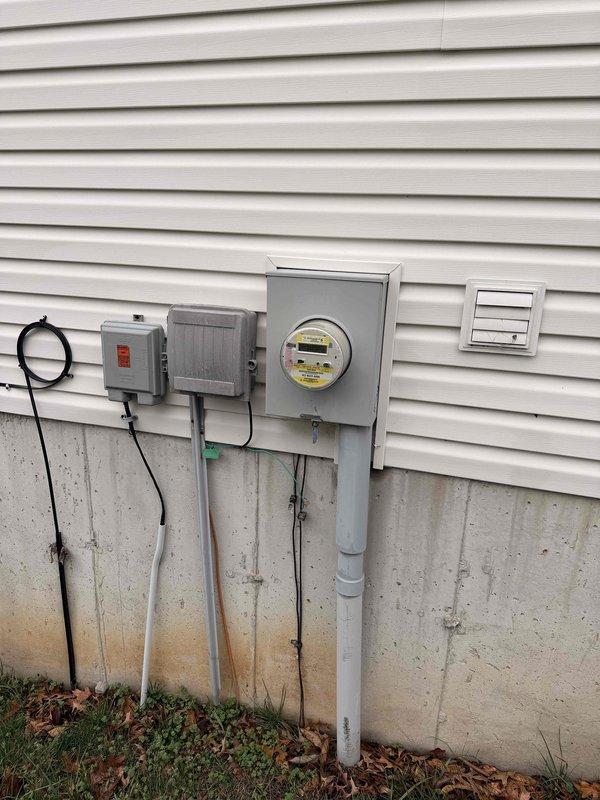 Completed complimentary electrical home audit, inspecting main service panel and exterior meter installation. Panel inspection revealed properly labeled circuit breakers with manufacturer documentation intact. Exterior evaluation showed standard service entrance configuration with digital meter and associated junction boxes mounted to vinyl siding. No immediate safety concerns identified.
