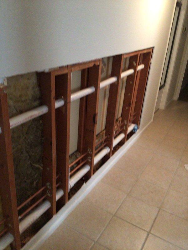 Completed installation of PVC plumbing infrastructure for first floor laundry relocation per permit #26PLU-04091. Work included removal of bathroom fixtures and opening walls to install 2" Schedule 40 PVC drain lines from new laundry location to main stack, along with necessary water supply lines. Additionally installed dryer vent flue through dining room wall with custom soffit and exterior wall penetration.