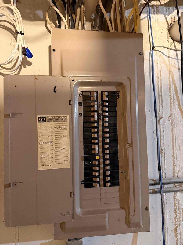 Completed annual electrical inspection, examining the main breaker panel which showed proper circuit organization but evidence of possible water damage on surrounding wall. Inspected exterior electrical meter installation with PVC conduit, noting normal operational status but minor weathering on the housing and mounting surface.