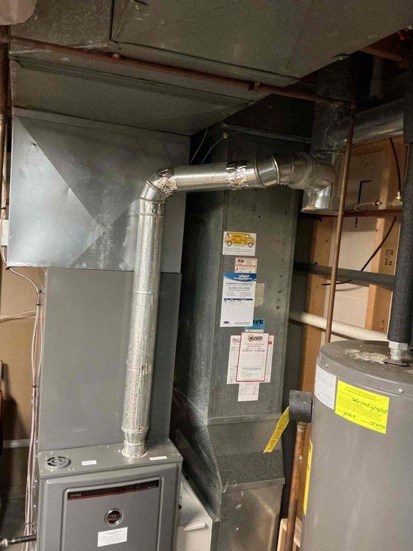 Successfully completed replacement of deteriorated flue pipe on HVAC system, installing new galvanized steel ductwork including multiple 4" pipe segments, 90-degree elbows, and appropriate reducers. System is now properly vented with secure connections and sealed joints, restoring safe and efficient operation of the heating unit.