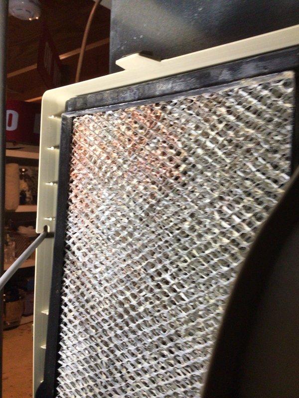 Responded to service call for leaking humidifier in HVAC system under 10 years old. Inspection revealed severely clogged air filter with significant dust accumulation and reddish-brown staining throughout the diamond-patterned mesh. Filter was replaced to restore proper airflow and address moisture issues causing the humidifier leak.