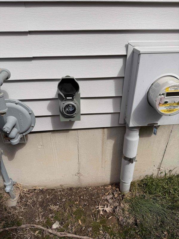Installed generator inlet on exterior of residential building, connecting to existing electrical panel. System includes exterior junction box mounted adjacent to gas and electric meters. Completed wiring connections at main breaker panel, ensuring proper integration for standby power capability.