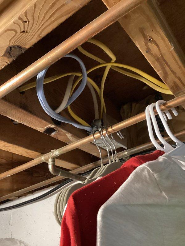 Performed comprehensive electrical inspection of residential property, focusing on unfinished basement area with exposed wiring systems. Evaluated multiple electrical cables (various colors) secured to copper pipes and joists, and inspected main electrical panel and networking setup including surge protection. Documented proper cable management and identified no immediate safety concerns with the current installation.