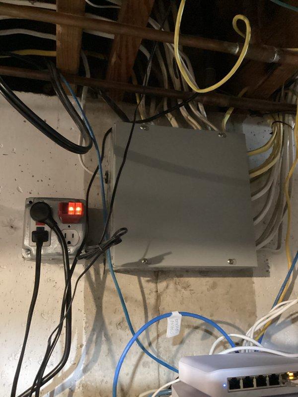 Performed comprehensive electrical inspection of residential property, focusing on unfinished basement area with exposed wiring systems. Evaluated multiple electrical cables (various colors) secured to copper pipes and joists, and inspected main electrical panel and networking setup including surge protection. Documented proper cable management and identified no immediate safety concerns with the current installation.
