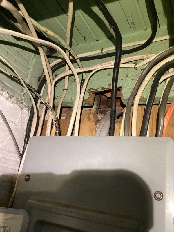 Conducted free electrical inspection of residential panel system. Observed aging infrastructure with disorganized wiring bundles and conduit installation against wooden structural elements. Panel inspection revealed multiple circuit breakers with inadequate labeling and suboptimal wire management that may require future organization to meet current electrical code standards.